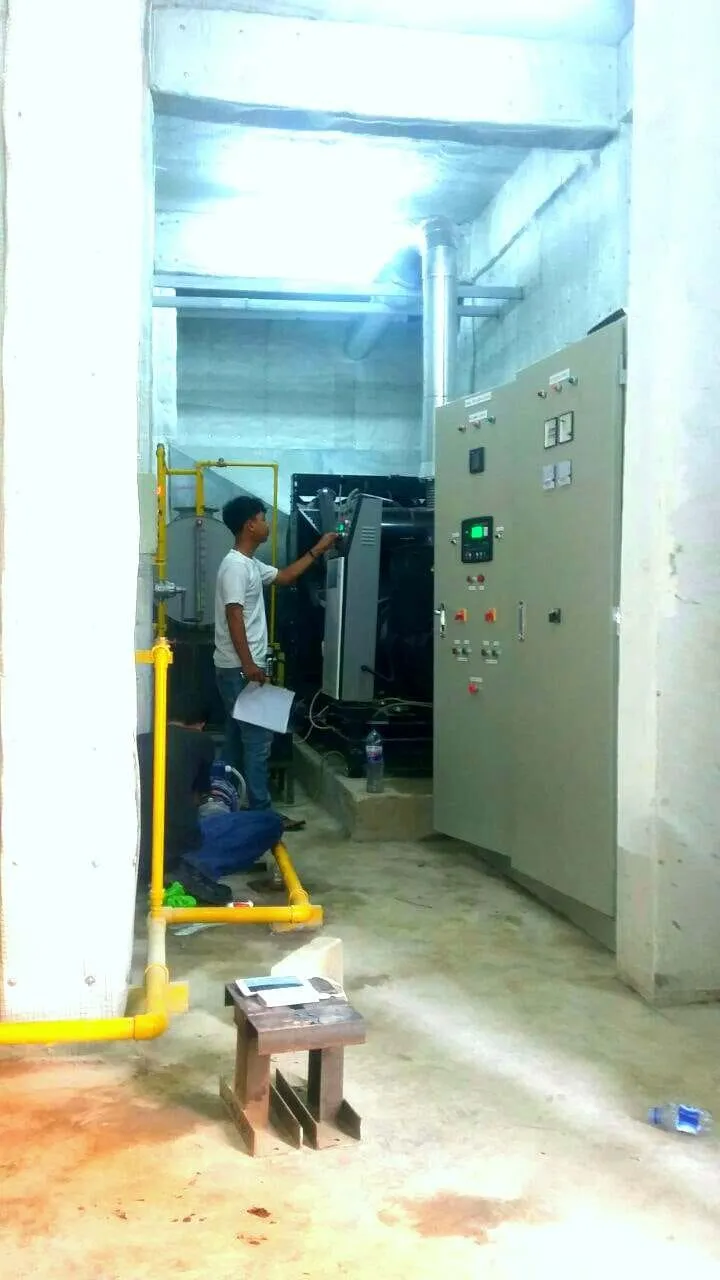 Teknisi memeriksa panel kontrol genset di ruang mesin dengan instalasi pipa gas