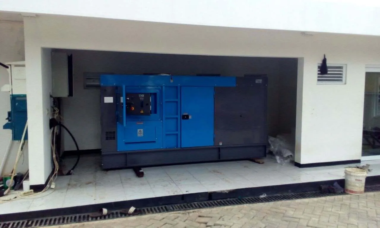 Genset silent type warna biru terpasang di area di bangunan komersil
