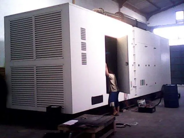Genset Volvo silent type warna putih kapasitas besar dengan teknisi membuka pintu akses di workshop